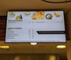 A high-definition digital menu board in a restaurant setting, showcasing "From the Griddle" breakfast items and customizable omelet toppings to enhance customer ordering experiences.