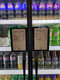 Retail refrigerator doors displaying "Good Stuff to Go" digital menu boards above assorted bottled beverages.