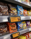 A retail store shelf stocked with various candy bags featuring digital electronic shelf labels.