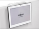 "A clear bin clip securing a digital display label onto the edge of a white shelf.