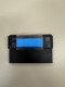 A clear tape mount bracket attached to the back of a black electronic shelf label.