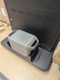 Grey Anker SOLIX portable power station sitting in a black mounting tray at the base of a digital display.