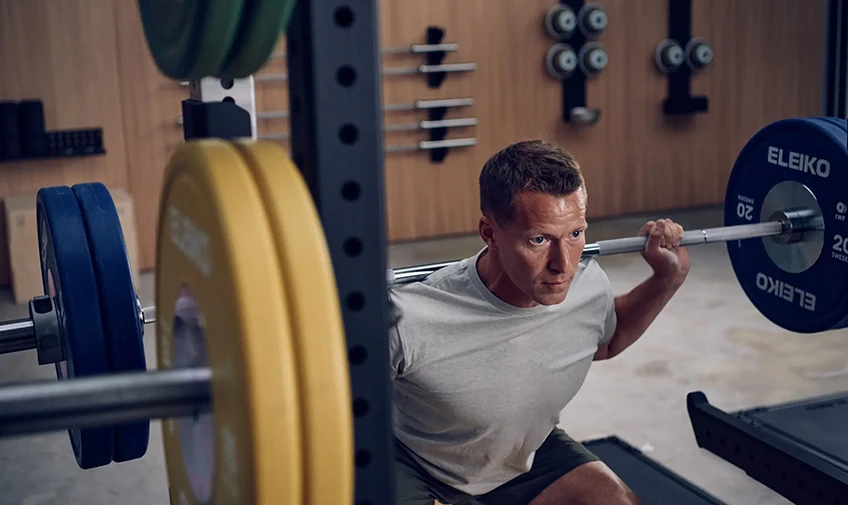 Athlete squatting inside an Eleiko Prestera rack with optimized upright geometry