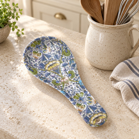 William Morris blue floral melamine spoon rest on a kitchen benchtop beside a pottery utensil jug