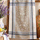 French-made beige Christmas Reindeer Jacquard tea towel displayed in a rustic festive kitchen with Christmas greenery and warm lights