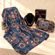 Blue abstract print shawl with a brown La Garde Freinet necklace, patterned cosmetic bag and black gift box with burgundy ribbon.