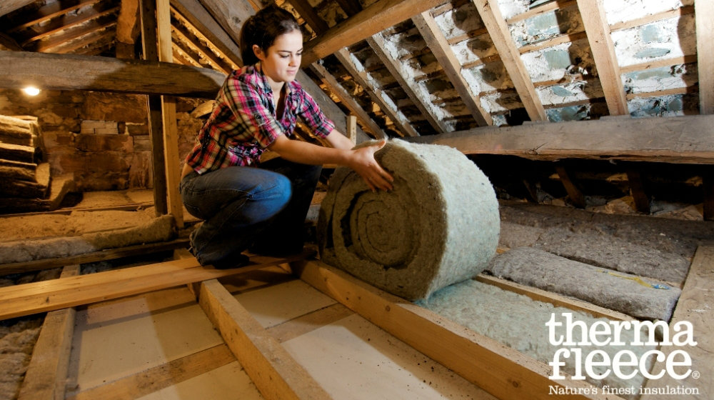 Thermafleece cosywool insulation roll being installed by lady in an attic