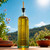 16.9 oz Tuscany Oil or Vinegar Bottle with Gold Spout with Olive Oil Outside on Picnic Table