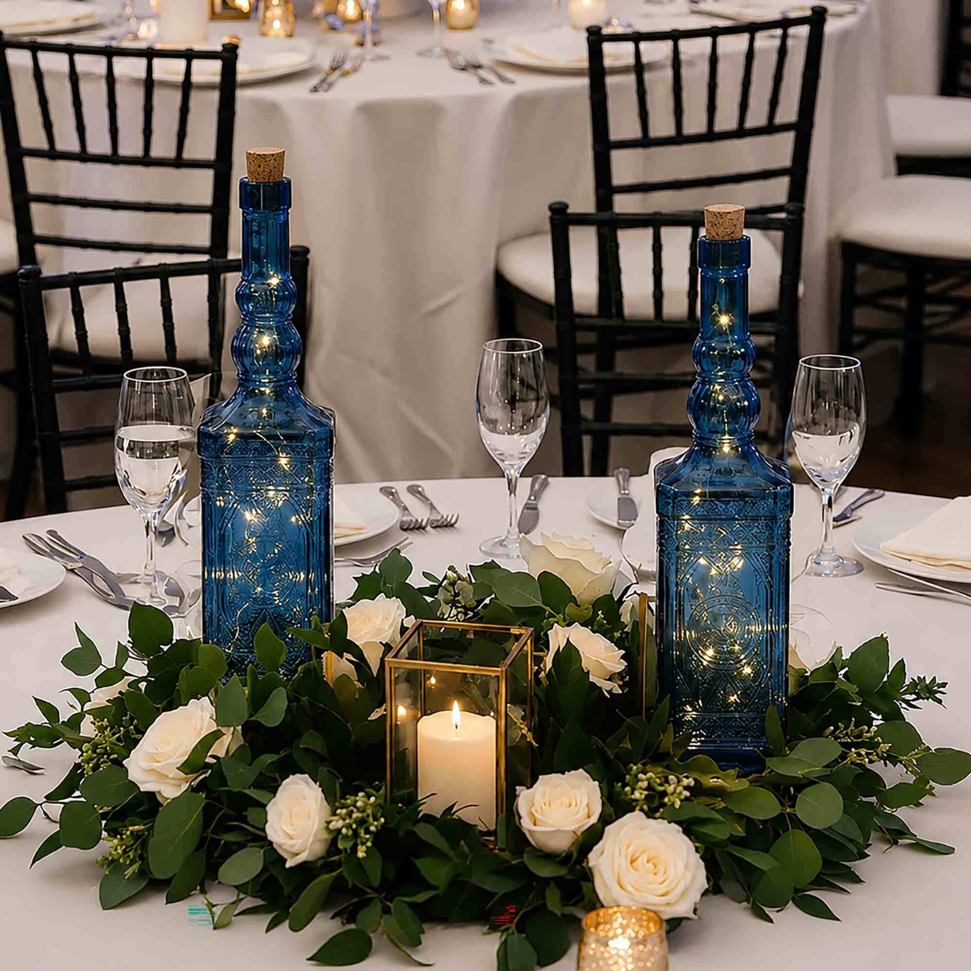 Ornate Blue Bottles with String Lights on Wedding Reception Table as Centerpiece with Roses