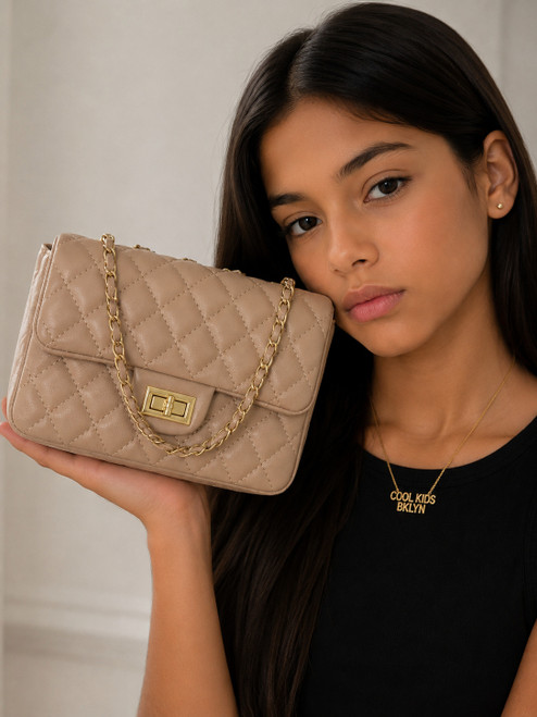 Girl modeling the Coco Quilted Junior tauped quilted handbag with gold hardware and chain strap.