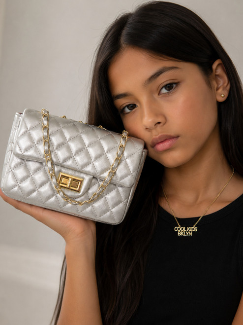 Girl modeling the Coco Quilted Junior silver metallic quilted handbag with gold hardware and chain strap.