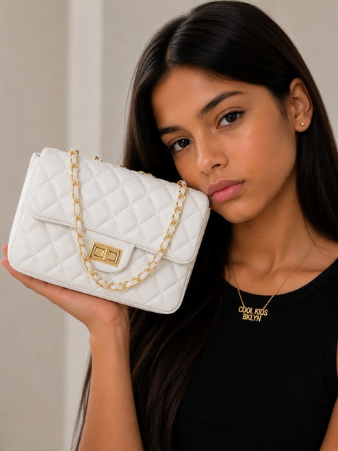Girl modeling the Coco Quilted Junior white metallic quilted handbag with gold hardware and chain strap.coolkidsbklyn
