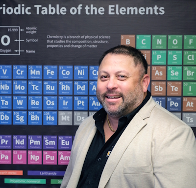 Erik Miller standing in front of a periodic table of elements