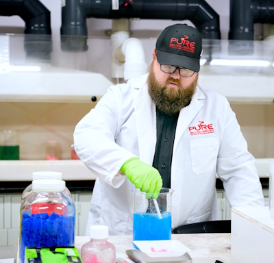 A person in a lab coat mixing a liquid in a beaker