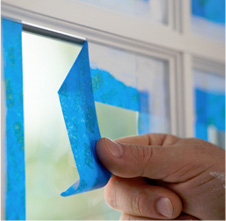 Image of person removing from window frame a strip of blue painters tape from iTapeStore.com