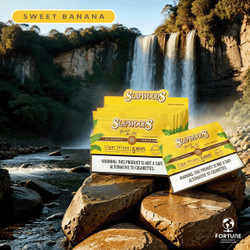 Slapwoods Natural Leaf Cigar Wraps Sweet Banana, vibrant yellow packaging with green leaf design, displayed in front of a scenic waterfall background