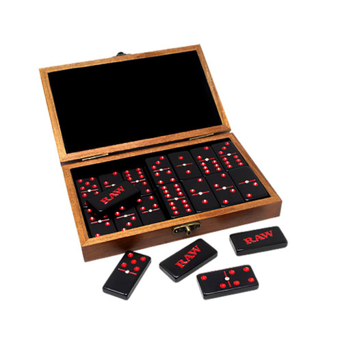 RAW Dominoes Double Six 28pc Set, a wooden box containing black domino tiles with red and white dots, some tiles with the 'RAW' logo, and a few tiles displayed outside the box for playing.