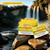 Slapwoods Natural Leaf Cigar Wraps Sweet Banana, vibrant yellow packaging with green leaf design, displayed in front of a scenic waterfall background Slapwoods Natural Leaf Cigar Wraps Sweet Banana, vibrant yellow packaging with green leaf design, displayed in front of a scenic waterfall background