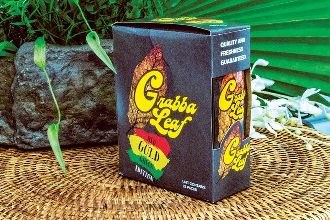 Grabba Leaf Tobacco Grabba Leaf Wraps Red Gold Green Edition 25ct, product packaging with colorful branding design on a textured surface, surrounded by natural elements.