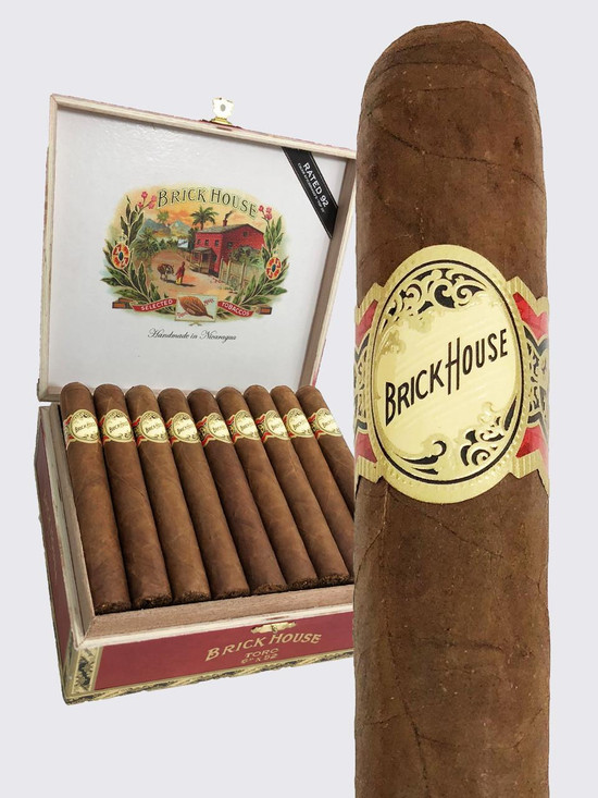 Brick House Toro Cigars 25Ct. Box, a collection of handmade cigars with a cigar on the right showing the label, and a decorated box of cigars in the background.