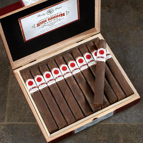 Rocky Patel Sun Grown Maduro Cigars, a box of premium cigars with dark, Maduro wrappers and individual labels, some cigars arranged in a neat row with one slightly pulled out.
