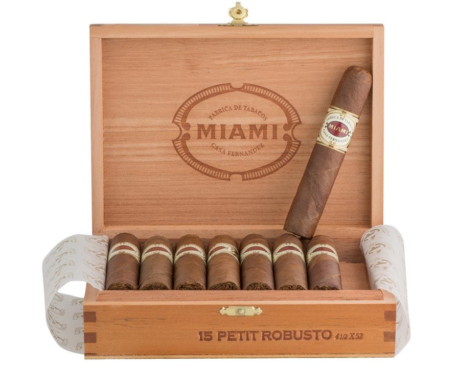 Casa Fernandez Miami Petit Robusto Cigars 15Ct. Box, open wooden box containing 15 cigars with one cigar outside the box, featuring a classic cigar band design. Casa Fernandez Miami Petit Robusto Cigars 15Ct. Box, open wooden box containing 15 cigars with one cigar outside the box, featuring a classic cigar band design.