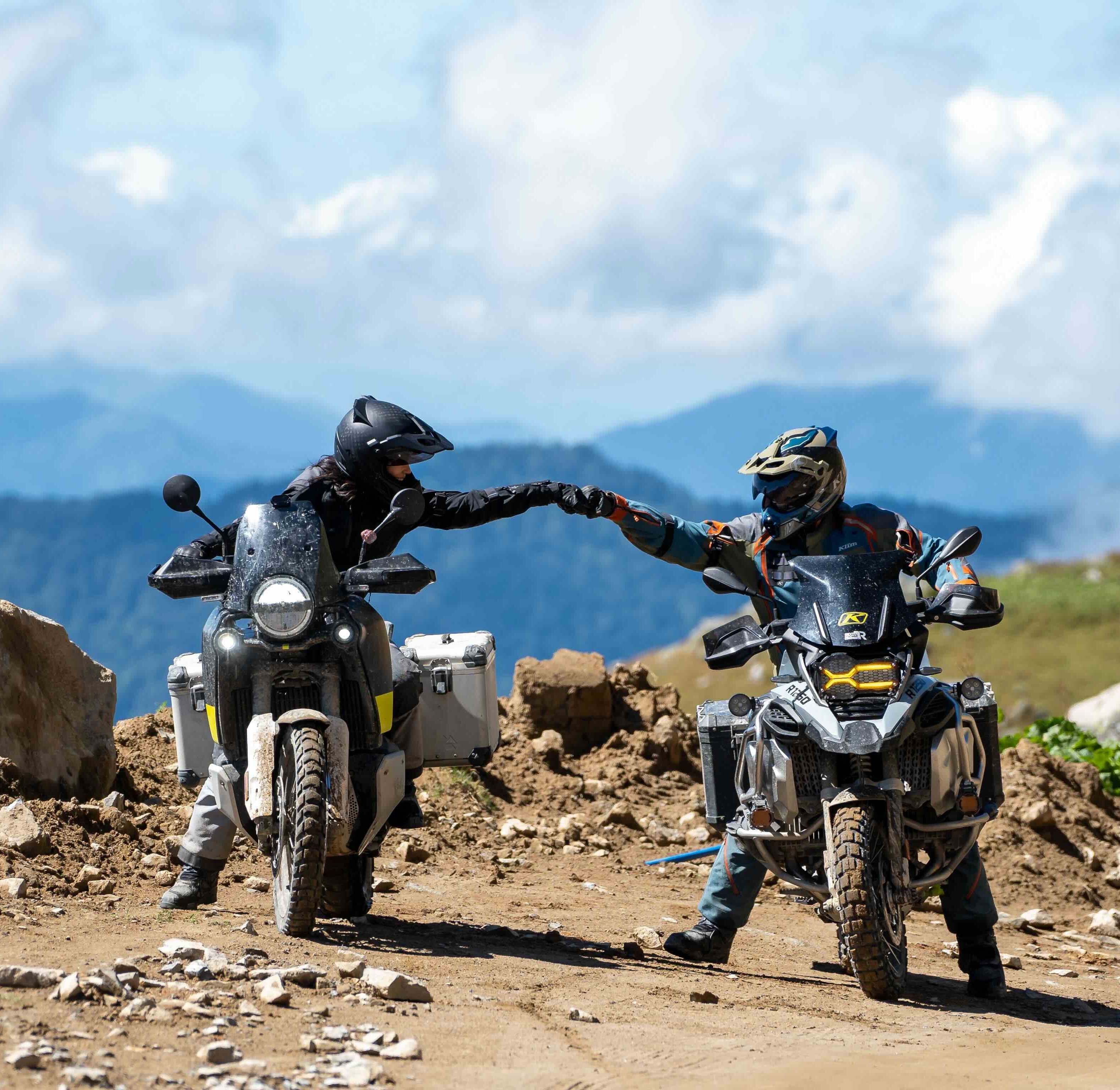 two riders on mortorcycles fist bumping