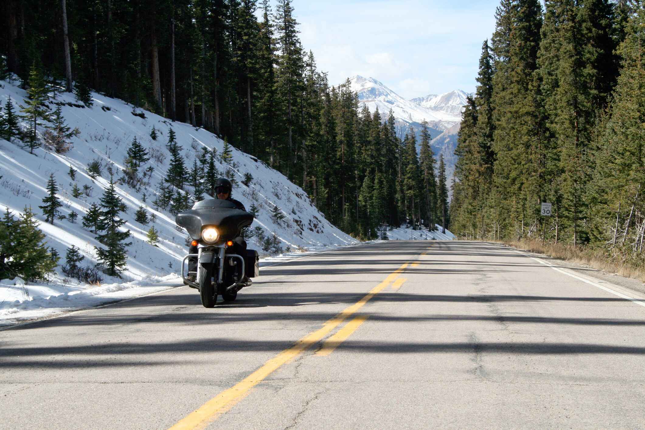 person riding a motorcycle down a road with snow on the sides