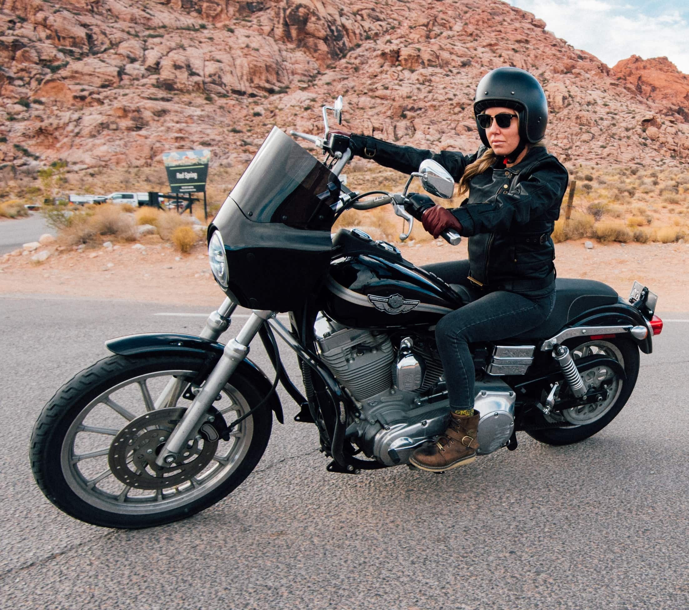 woman riding a motorcycle with a mountain behind her