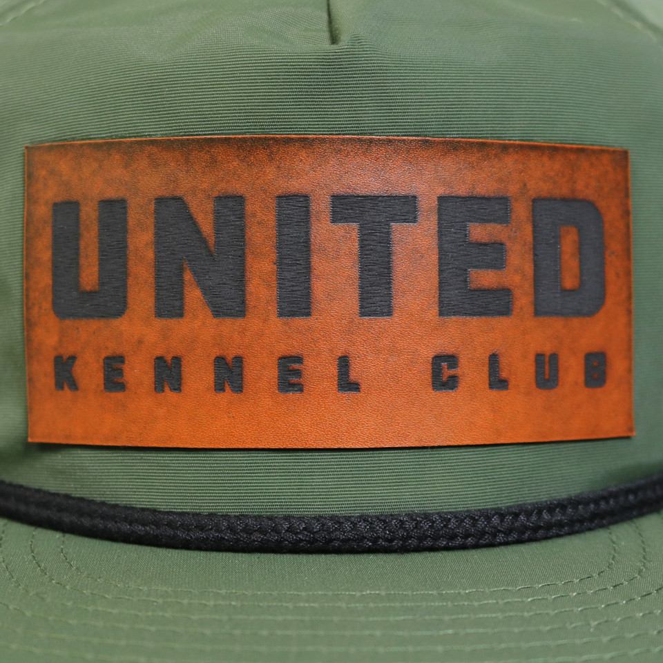 Green ripstop flat bill hat with rope detail, featuring a faux leather United Kennel Club logo patch on the front. Water-resistant, UPF 50+, and made with a recycled plastic bill.