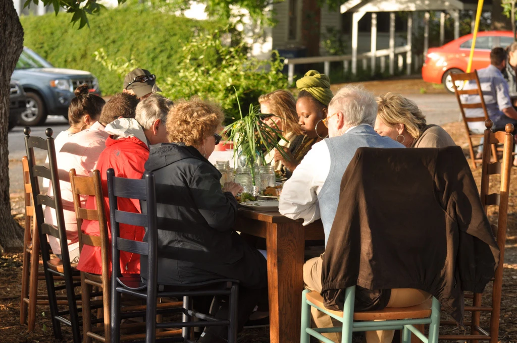 Guests dining around a table with colorful solid wood Troutman chairs