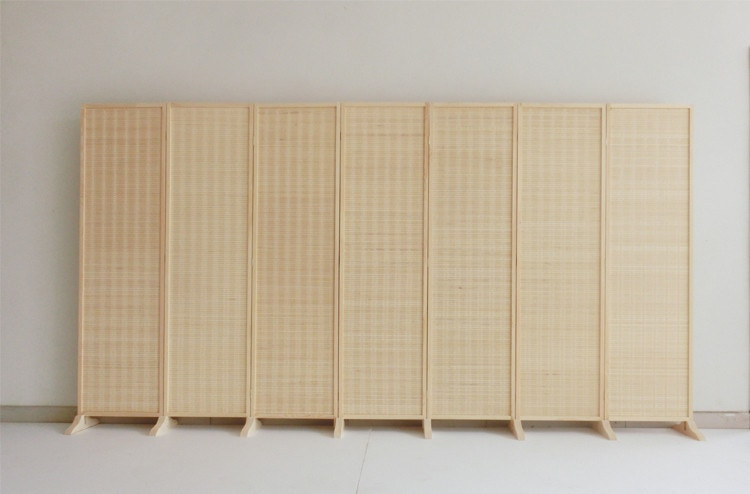 Front view of seven-panel bamboo room divider against wall