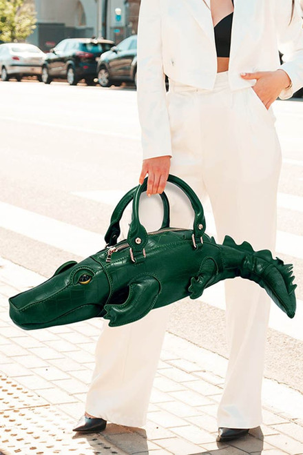Novelty handbag designed in a crocodile-inspired shape with sculpted details and top handles. This playful statement purse adds bold personality and artistic style to outfits while offering a unique conversation-starting accessory for fashion lovers and special events. PROM AVENUE 