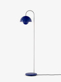 A cobalt blue Flowerpot VP12 floor lamp features a round base, a slender silver pole curving to suspend a blue domed shade, with a smaller spherical shade inside. A black cord extends from the base
