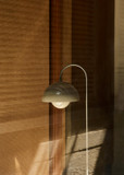 Close-up of a Flowerpot VP12 floor lamp, showing its polished chrome frame, translucent dome shade with a white inner sphere, against a textured light brown wall.