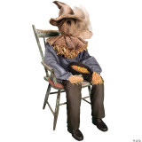 Morris Sitting Scarecrow Animated, scarecrow dressed as an elderly person sitting on a rustic wooden chair holding a bowl of colorful candy corn.