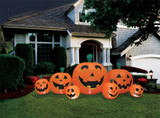 Seasonal Visions Pumpkin Patch 8.5' Long Inflatable, large orange inflatable Halloween pumpkins with smiling faces decorating the front yard of a suburban house at night.