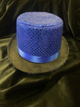 Fantasy Costumes Sequin Top Hat - Blue, shimmering blue top hat with sequins and a satin ribbon band, resting on a black velvet fabric for a glamorous costume accessory.