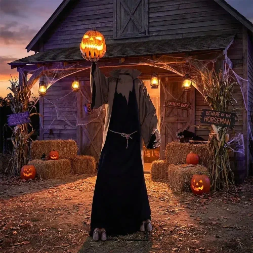 Morris Animated 9 Ft. Light-Up Night Dweller Halloween Decoration, eerie long black cloaked figure with lit pumpkin head standing in front of a haunted barn decorated for Halloween with pumpkins, hay bales, and spooky signs.