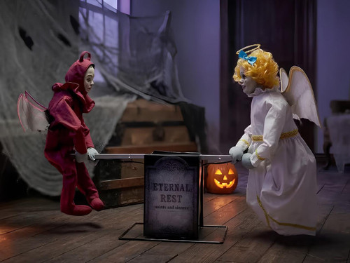 Morris Animated Angel Devil Seesaw Halloween Decoration Prop featuring a red devil and a white angel dolls playing on a seesaw with a Halloween-themed pumpkin lantern in the background.