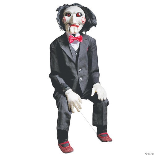 Trick or Treat Studios Billy Puppet Prop - SAW, a life-size horror puppet costume with a sinister clown face, black hair, and dressed in a black suit with a red bow tie, sitting with a white background.