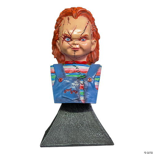 Trick or Treat Studios Bride Of Chucky Mini Bust, detailed collectible bust of Chucky's Bride with distinctive facial scars and red hair, wearing a colorful striped shirt and blue overalls with "Good Guy" embroidery, mounted on a textured black base.