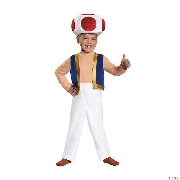 Disguise Super Mario Bros.™ Toad Toddler Costume 3T-4T, a young boy wearing a Toad costume with a large white mushroom cap with red spots, a blue vest with gold trim, beige shirt, white pants, and brown shoes, smiling and giving a thumbs-up.