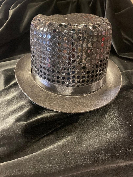 Fantasy Costumes Sequin Top Hat - Black, a stylish black top hat with sequins and perforated design, placed on a satin fabric background.