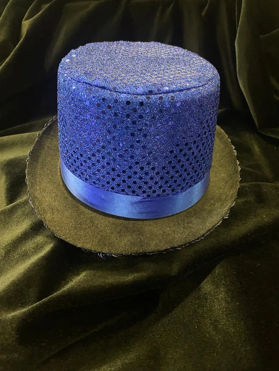 Fantasy Costumes Sequin Top Hat - Blue, shimmering blue top hat with sequins and a satin ribbon band, resting on a black velvet fabric for a glamorous costume accessory.