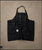 Change The Course Apron in black denim, laid flat with pocket detail visible