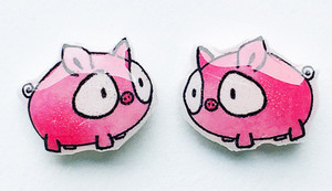 Small handmade pig stud earrings with pink animal design and expressive eyes shown on a clean background.
