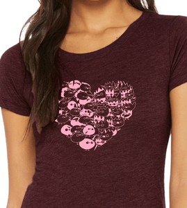 Close up of woman wearing Heart shaped design made of battling pink and red monster characters. Bella Canvas scoop neck tee. Color maroon.