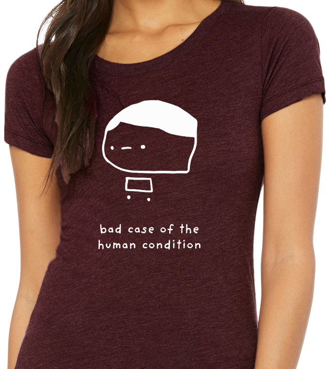 Close-up of simple hand-drawn character illustration with humorous existential phrase on maroon tee.
