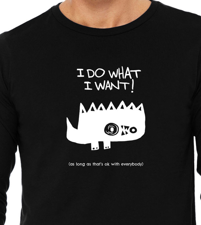 Close-up of spiky cartoon monster illustration with humorous polite rebellion quote on black tee.